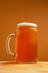 Pint of American Pale Ale in Jar Mug on a beer colored background 