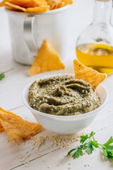 Traditional arabian eggplant dip baba ganoush with corn chips on white wooden table