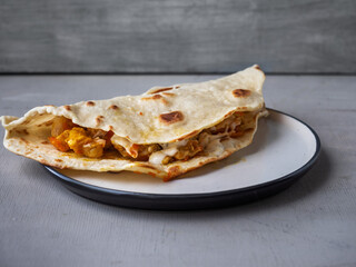 Hot quesadilla with chicken and vegetables on a round plate close-up