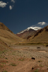 Mountaineering. View of mountain Aconcagua, highest peak in America. Stream flowing downhill across the desert and hills.