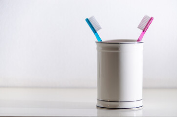 Pair of toothbrushes in a porcelain jar.