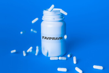 Chuva de comprimidos de FAVIPIRAVIR sobre a embalagem de FAVIPIRAVIR ao fundo azul