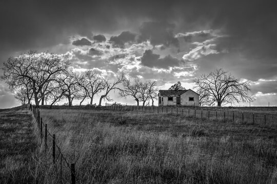 A black and white photo of an old abandoned house on a hill on the Great Plains