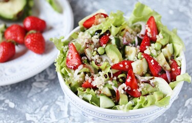 Salad with strawberries, quinoa, avocado, cucumber, lettuce, onions and green peas. vegetarian food.copy space