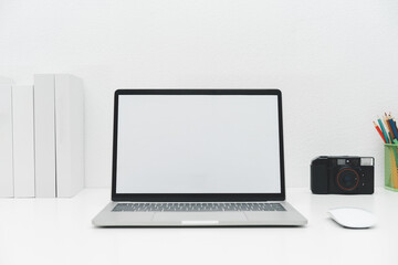 Laptop mockup with blank screen on white table with mouse. Home interior or office background