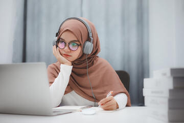 Beautiful muslim student girl using a laptop computer learning online at home. Distance learning...