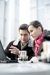 Couple sharing laptop at a cafe
