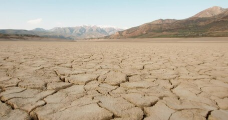 Dynamic shot of cracked soil ground of dried lake or river in mountains. Land destroyed by erosion and global warming - ecological issues concept 4k footage