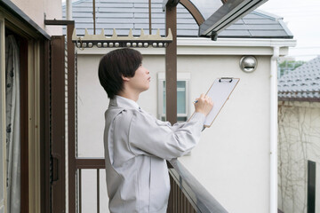 住宅　バルコニーのサンルーフを調査するビジネスマン
