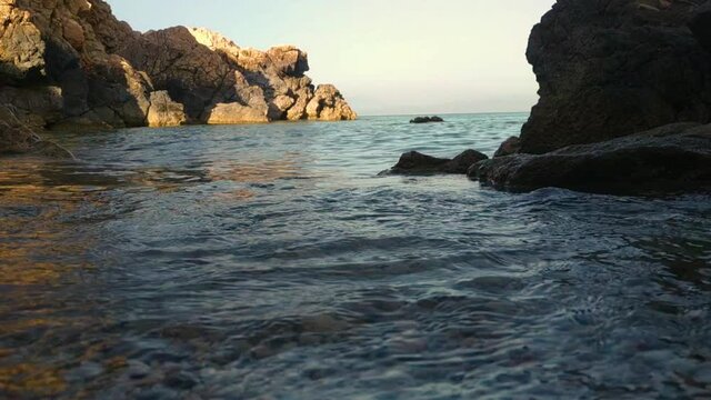 Close up of waves current against rocky shore on sunny day in Sardinia, Italy, summer vacation