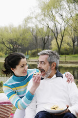 Woman feeding her husband while picnicking in the park