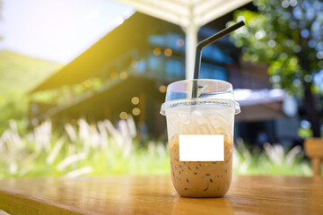 Cold coffee mug with white label for logo blurred coffee shop background.