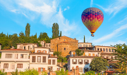 Fototapeta na wymiar Colorful hot air balloon flying over Sirince village - Traditional turkish (ottoman) village house in Sirince - İzmir, Turkey 