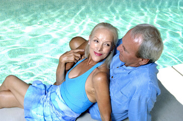 Old couple relaxing by the pool side