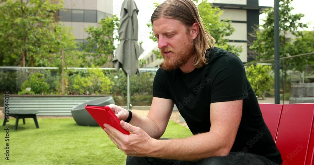 Poster a middle aged man opens up his e-reader or tablet and scrolls through the options to find what he is