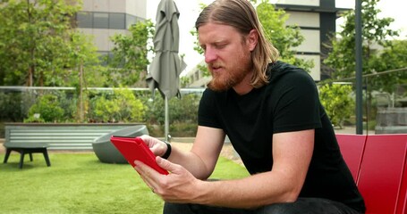 A middle aged man opens up his e-reader or tablet and scrolls through the options to find what he is looking for. - Powered by Adobe