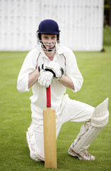 Obraz premium Man kneeling down while holding a cricket bat