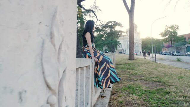 steady cam on beautiful woman sitting on a wall looking serious at camera