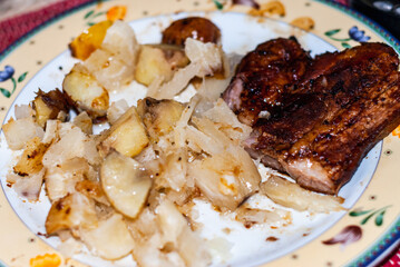 Dish with steaks cooked in a pan with onions, Andean potatoes, fine herbs and spices, accompanied with cassava in brine. Selective focus.