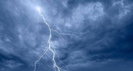 Lightning strikes between blue stormy strange clouds.