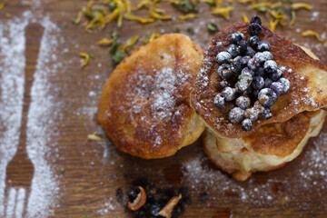 Close-up of fritters with fresh blueberries in icing sugar on a wooden table