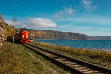 Red train going on Circum-Baikal Railway around baikal lake on sunny day, Siberia, Russia