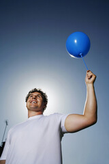 Man smiling while holding a blue balloon