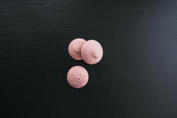 Naklejka premium pink meringues on a dark wooden background