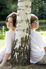 Fototapeta premium Boy and girl sitting under a tree