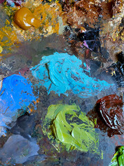 Artist's oil paint palette. Macro textured paint smudge. Art color mixing closeup. Green, blue, sienna colour shades swatches. Vibrant paint stain. Multicolor tones, Earth colors blend for painting. 