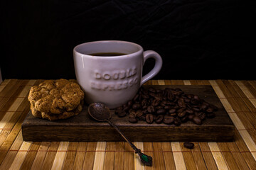 White cup of coffee on wooden tray with cookies and coffee beans