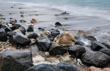 Long exposure photo of stones on the sea water at the beach