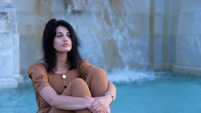 pensive sad lonely woman lowering her head sitting with crossed legs