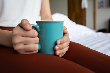 Woman hands holding green ceramic cup.