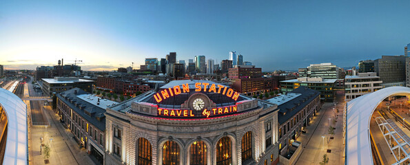 union station panorama with neon travel by train sign and clock and Denver city skyline in the...