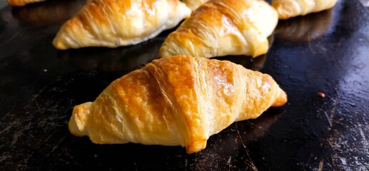 Croissants fresh from the oven in a bakery on a heat resistant metal tray