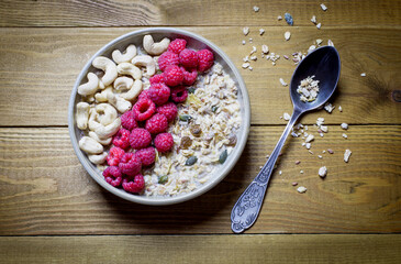 Healthy Breakfast with muesli, cashew nuts and fresh raspberries on a wooden background. Copy space