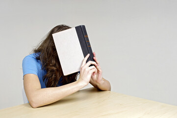 Woman covering her face with a book