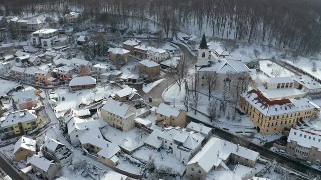 Aerial view of the Liboc city district in Prague. The church of the St. Fabian and Sebastian standing on the hill above the houses. Fresh snow covering roofs, walkways, and lawns.