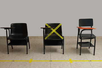 empty desks spaced one meter apart marked with yellow tape and distance markings on the pi