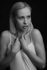 Naklejka premium black-and-white portrait of a blonde on a black background. in a white tank top with straps