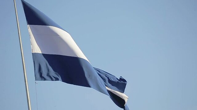 The flag of the country of El Salvador waving on a sunny day.