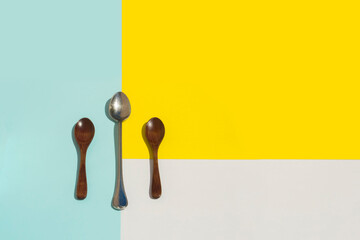 one metal and two wooden spoons on a blue yellow and white background. with copy space
