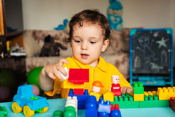 Cute boy child playing at home with colored cubes