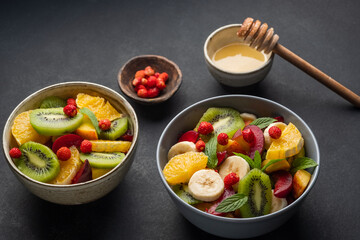 Concept of low calories delicious desserts. Summer fresh bowl with colorful fruit salad. Healthy natural organic food. Tasty sweet snack. Black background. 