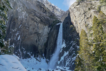 Wonderful waterfall and Half Dome at Yosemite Valley in the winter with white snow covering the trees