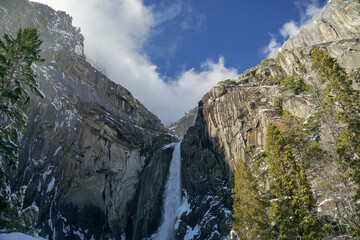 Wonderful waterfall and Half Dome at Yosemite Valley in the winter with white snow covering the trees