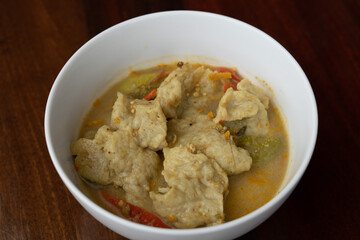 Thai food fish ball in green curry with egg plants and sweet basils in white bowl.