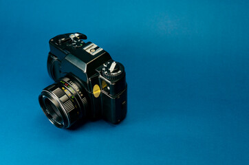 Analog black photography camera on a blue background