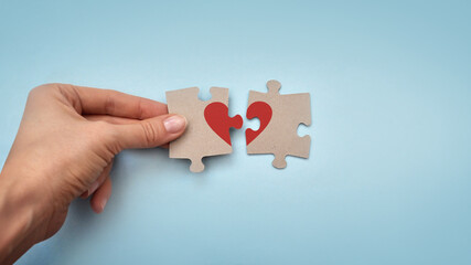 Two pieces of the puzzle with the image of a red heart. The joining of two halves into one